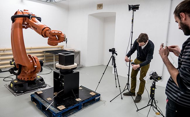 KUKA Industrieroboter wird von zwei Männern mit Kameras aufgezeichnet