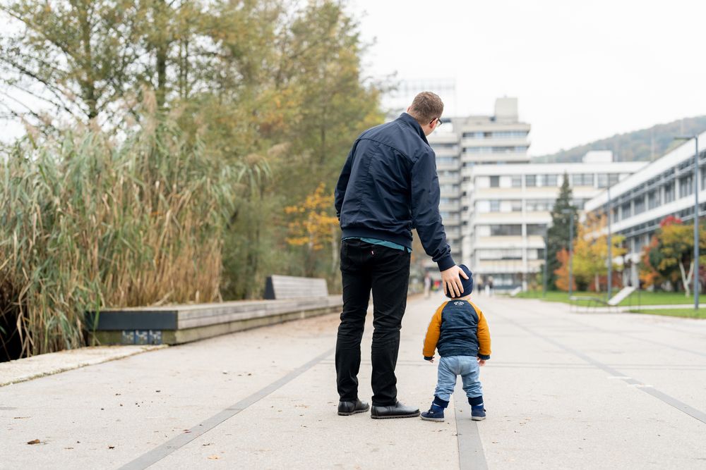 Vater und kleines Kind spazieren neben dem Uniteich