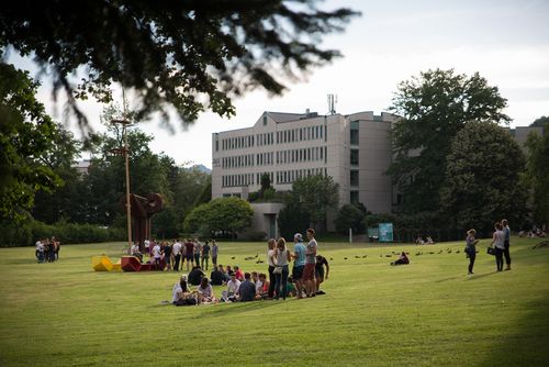 Studierende auf Wiese im Park, im Hintergrund das Managementzentrum