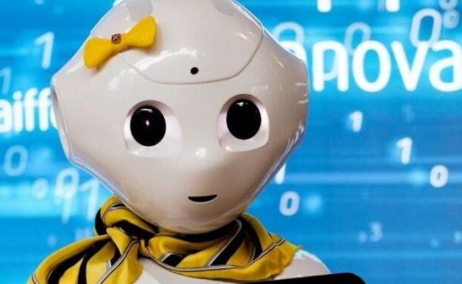 Der humanoide Roboter Pepper, gekleidet mit gelber Schleife und Halstuch und RLB-Logo.