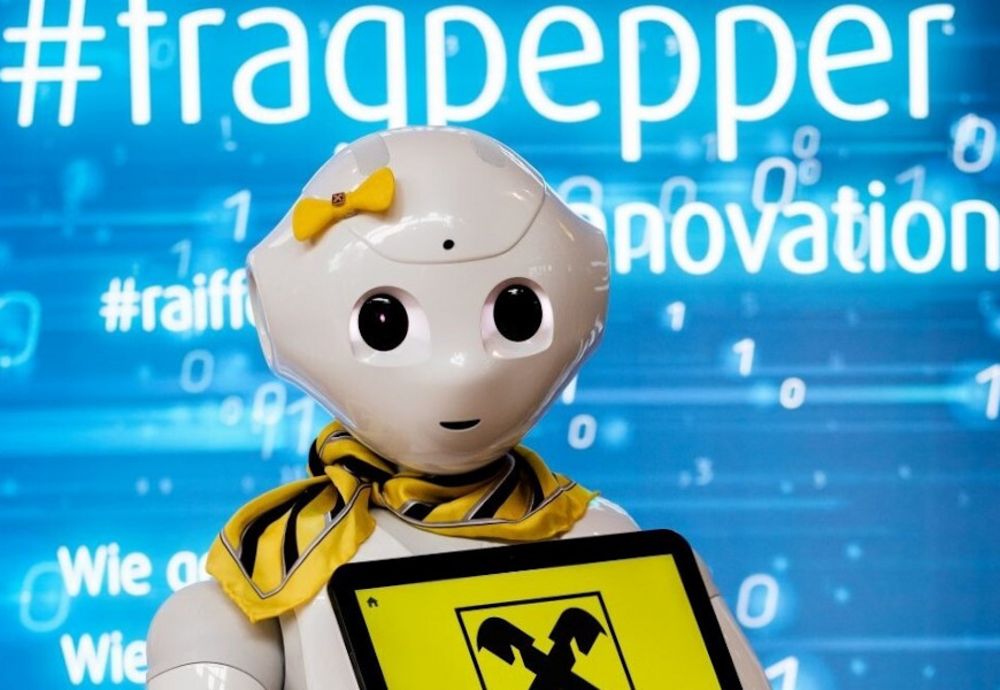 Der humanoide Roboter Pepper, gekleidet mit gelber Schleife und Halstuch und RLB-Logo.