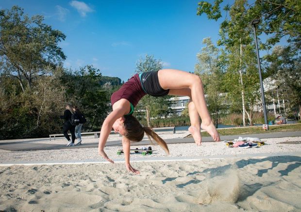 Studentin beim Flick Flack am Beachvolleyballfeld