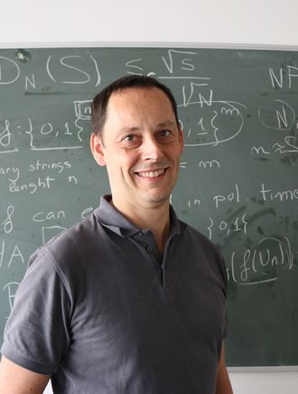 Das Foto zeigt das Institutsmitglied Friedrich Pillichshammer. Er steht vor einer mit mathematischen Formeln beschriebenen Kreidetafel.