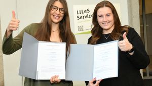 Julia Wolfinger and Anna Schörgenuber holding their diplomas