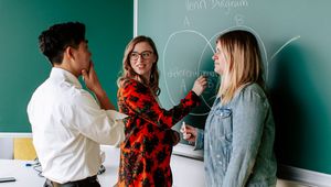 Drei JKU Studierende stehen vor einer Tafel und versuchen eine Aufgabe zu lösen