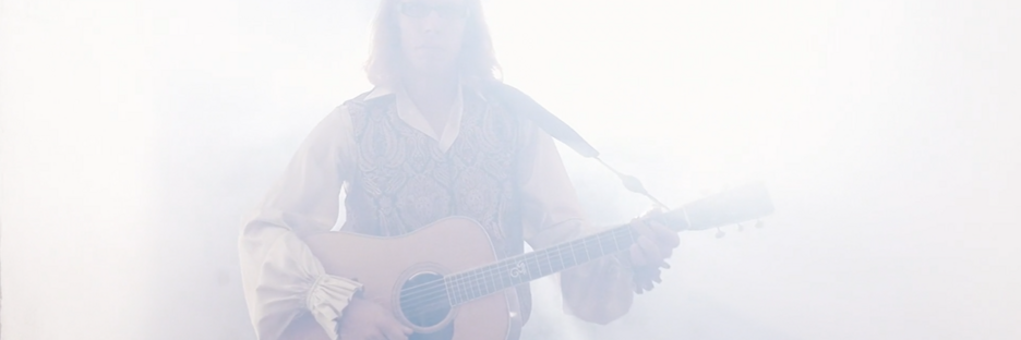 Mann mit Gitarre im erscheint hell angeleuchtet aus dem Nebel