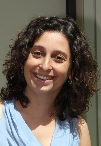Das Foto zeigt das Institutsmitglied Lucia del Chicca. Sie trägt eine hellblaue Bluse und hat dunklebraune, lockige, schulterlage Haare.