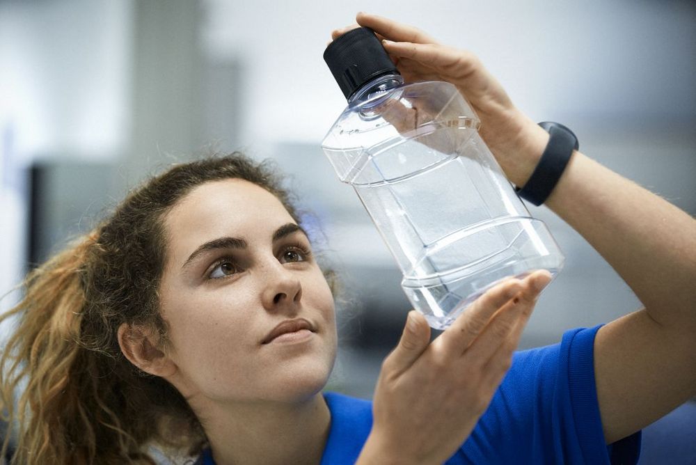 Technikerin begutachtet eine Kunststoff-Flasche