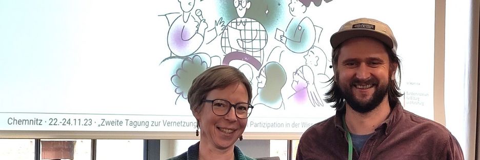 Kathrin Meyer und Thomas Meneweger vor dem Willkommens-Plakat der PartWiss-Konferenz