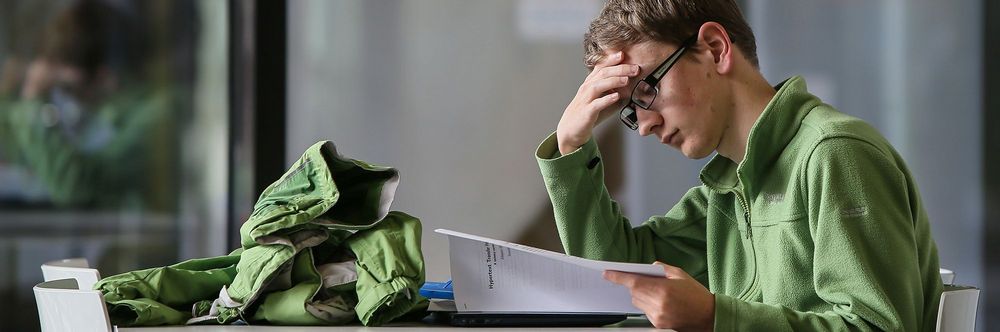 Studierender mit Unterlagen im Science Park sitzend