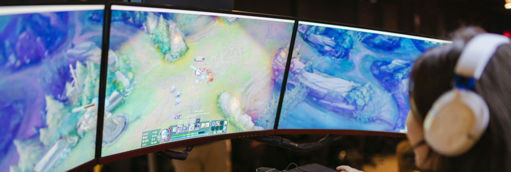 A woman playing League of Legends on three screens