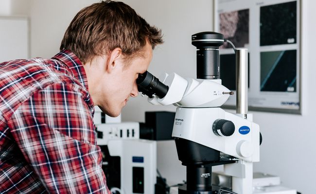 Studierender, der in ein Mikroskop schaut