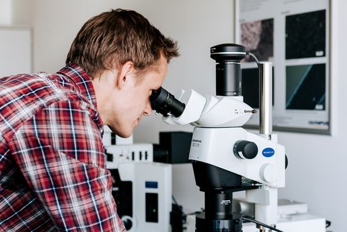 Studierender, der in ein Mikroskop schaut