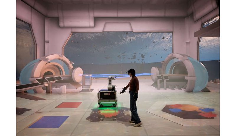 Person interagiert mit Controller mit mobilem Industrieroboter in einer virtuellen Spielumgebung