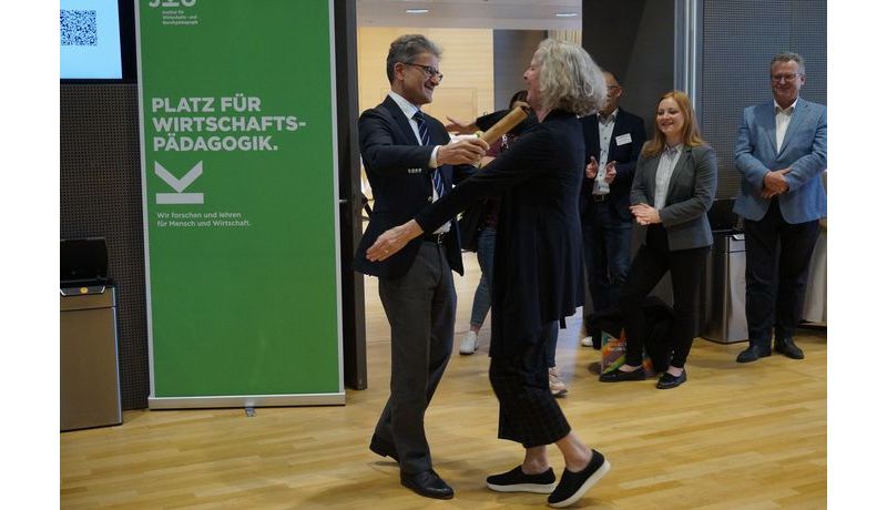 Prof. Neuweg hands the baton to Prof. Stock (University of Graz), hosts of the 2025 symposium; Photo credit: JKU